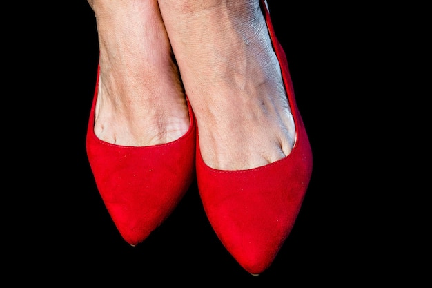 Piedi di donna con scarpe rosse su sfondo nero.