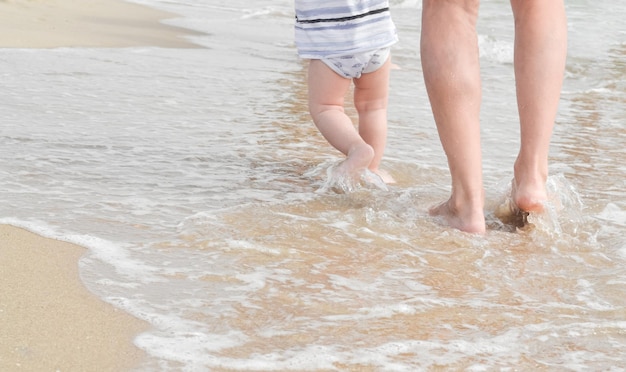 Piedi di mamma e bambino in riva al mare