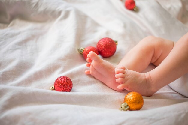 Piedi di un neonato su un bianco con i giocattoli di Natale