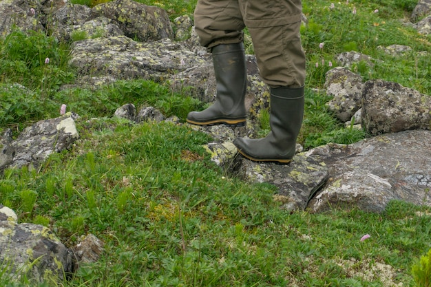 Piedi di un uomo con stivali di gomma che cammina in un paesaggio naturale