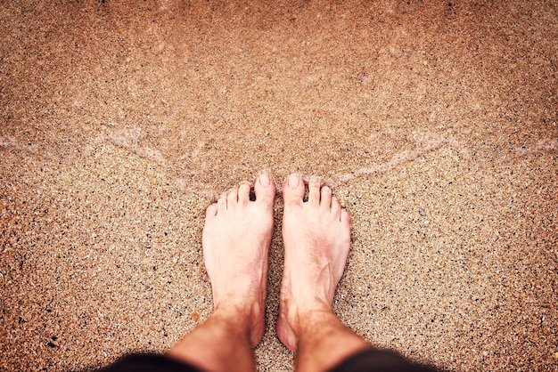 Piedi felici in spiaggia Inquadratura dall'alto dei piedi di una donna irriconoscibile in spiaggia