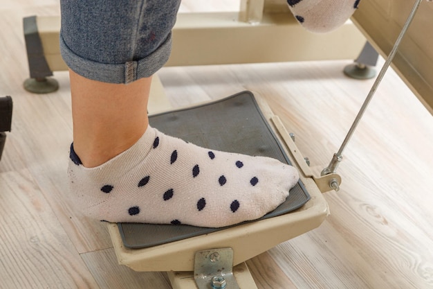 Piedi femminili sul pedale di un motore per macchina da cucire