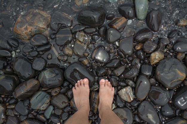 Piedi in piedi sulla spiaggia di pietre nere
