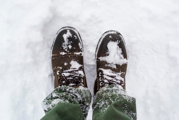 Piedi maschili con gli stivali che camminano lungo la neve d'inverno