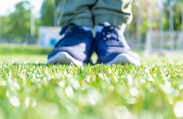 Piedi maschili in scarpe da ginnastica sportive in piedi sull'erba verde. Messa a fuoco selettiva