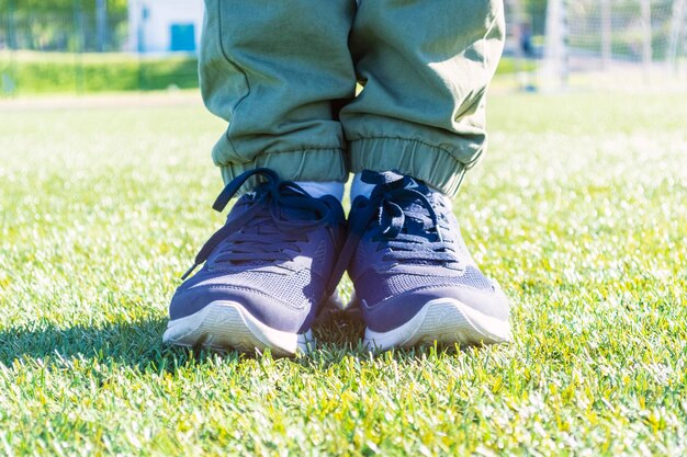 Piedi maschili in scarpe da ginnastica sportive in piedi sull'erba verde. Messa a fuoco selettiva