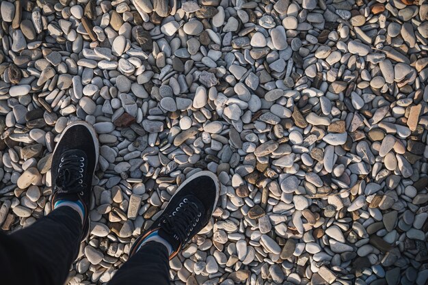 piedi maschili in scarpe da ginnastica stanno sulla strada fatta di pietra