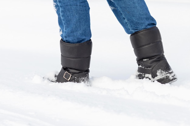 Piedi maschili in stivali neri, passeggiate invernali nella neve