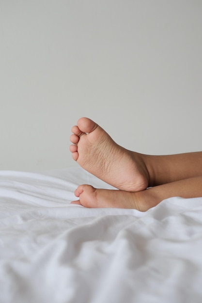 Piedi nudi dei bambini sul letto bianco