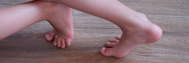 Piedi nudi del bambino che sta sul primo piano del pavimento di legno