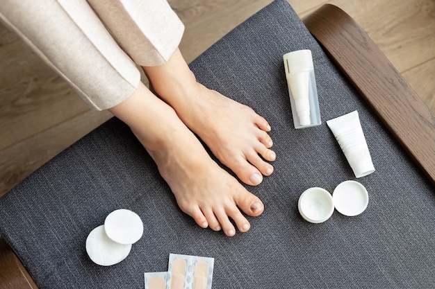 piedi nudi di donna con ferita all'unghia del piede e kit di assistenza medica.