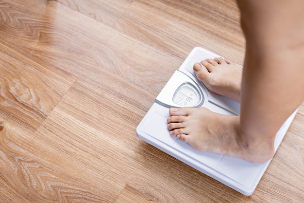 Piedi nudi femminili in piedi con una bilancia.