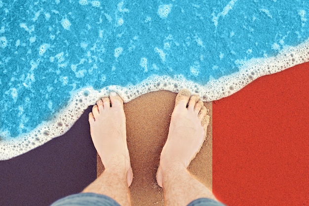 Piedi spiaggia con bandiera Francia sfondo mare Piedi maschili in sabbia vista dall'alto