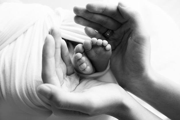 Piedini di un neonato nelle mani della mamma Il palmo amorevole di una madre Immagine concettuale della maternità Messa a fuoco selettiva del primo piano Fotografia professionale in bianco e nero