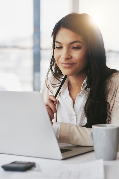 È piena di nuove idee Scatto di una giovane donna d'affari che lavora su un laptop in un ufficio