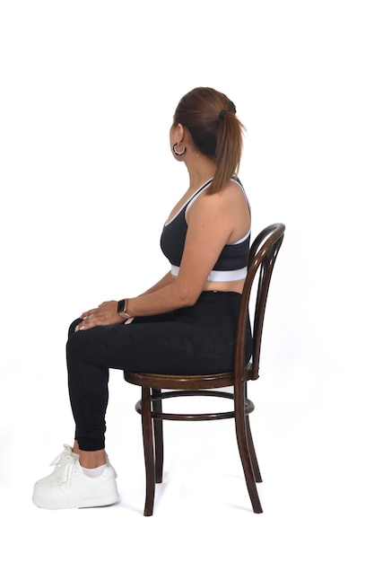 Piena vista di una donna seduta su una sedia e guardando indietro su sfondo bianco