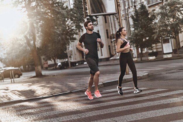 Pieno di energia. Per tutta la lunghezza della giovane coppia in abbigliamento sportivo che attraversa insieme la strada della città