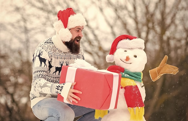 Pieno di felicità Babbo Natale regala attività all'aperto per la stagione invernale Buon Natale felice hipster pronto per le vacanze invernali di Natale maglione caldo nella stagione fredda uomo barbuto costruire pupazzo di neve