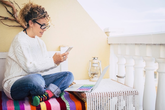 pieno di immagine a colori per la donna di mezza età che lavora libertà al laptop all'aperto in terrazza, vecchia lampada vintage sullo sfondo per un tipo alternativo di ufficio per lavorare in indipendenza