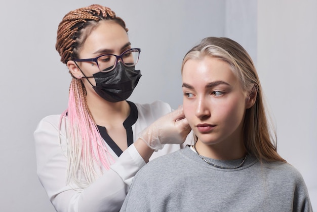 Piercing su un orecchio Conch e piercing ad elica si chiudono Professionista che tiene il gioiello