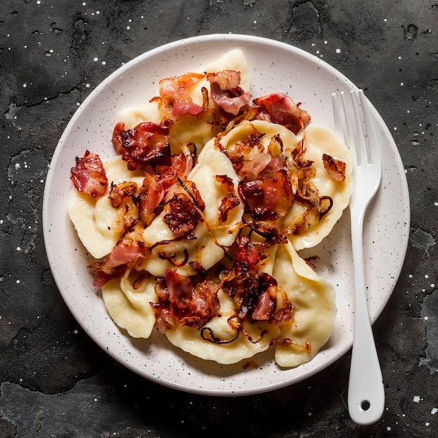 Pierogi di patate con pancetta fritta e cipolle delizioso pranzo fatto in casa su sfondo scuro