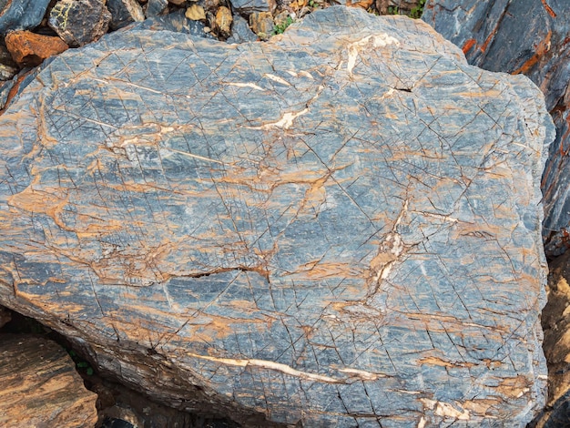 Pietra con licheni arancioni e primo piano delle crepe Sfondo naturale con pietra Struttura della pietra Minerale stupefacente Pezzo di roccia