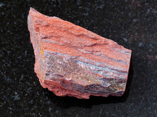 Pietra grezza di quarzite ferruginosa su fondo scuro