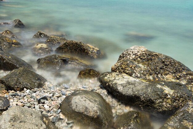 Pietra in mare e onda in mattinata con lunga esposizione