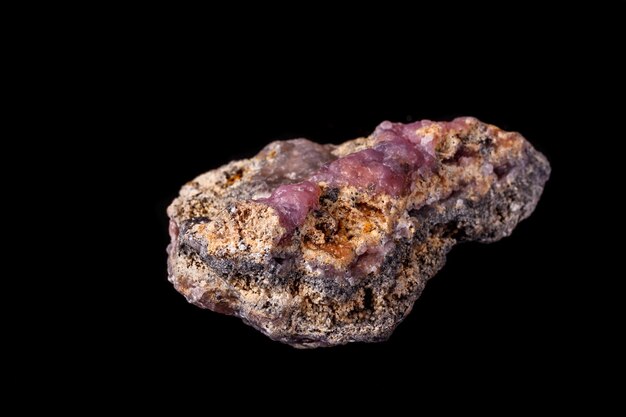 Pietra minerale Smithsonite rosa macro su microclino su sfondo nero