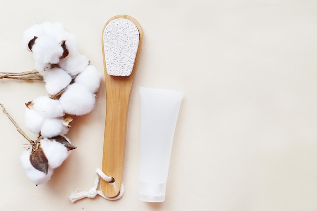 Pietra pomice ecologica per piedi con vasetto di crema mockup e fiore di cotone su sfondo beige