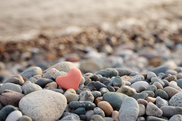 Pietra rossa a forma di cuore sulla spiaggia via mare