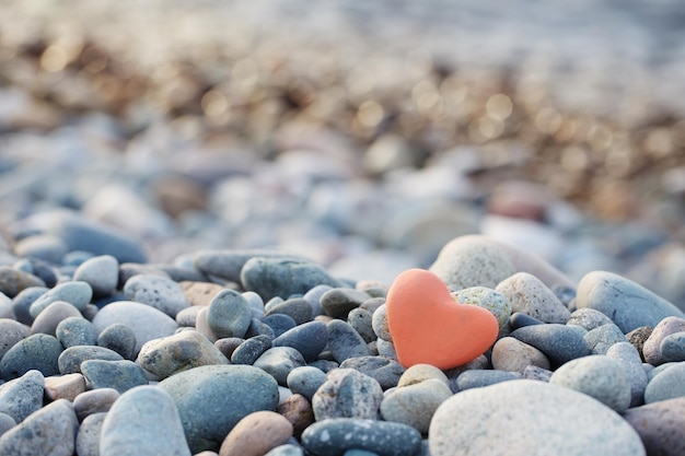 Pietra rossa a forma di cuore sulla spiaggia via mare