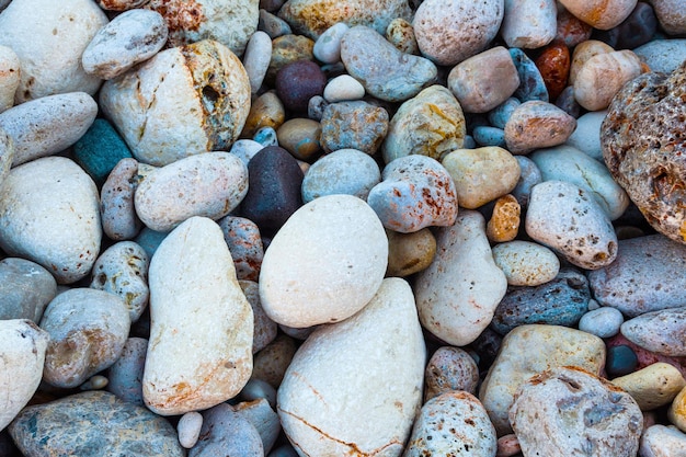 Pietre di diverse forme, dimensioni e colori sulla riva del mare in primo piano sullo sfondo delle pietre marine