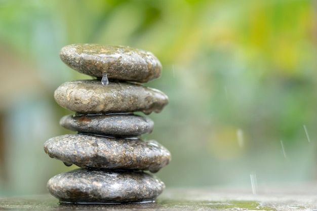 Pietre di meditazione con acqua goccia di pioggia sul pavimento di cemento su sfondo verde natura.