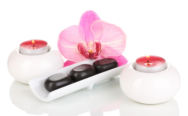 Pietre di spa con fiori di orchidee e candele isolate su bianco