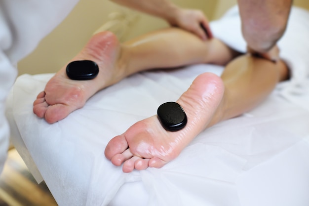 Pietre per la terapia della pietra ai piedi di una giovane donna. Relax, spa, massaggi