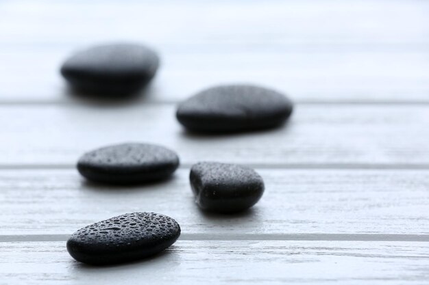 Pietre termali con gocce d'acqua su fondo di legno