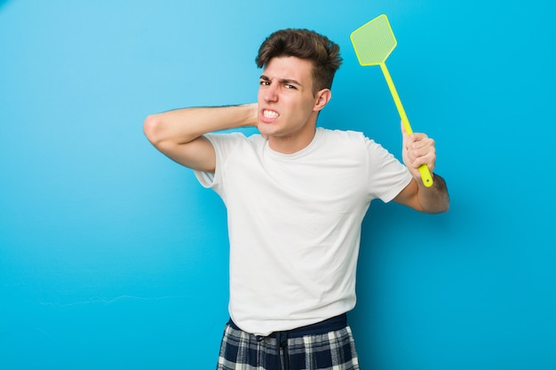 Pigiama da portare dell'uomo caucasico dell'adolescente e tenere un flyswatter