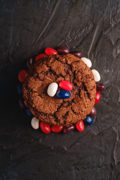 Pila casalinga dei biscotti del cioccolato dell'avena con cereale con i fagioli di gelatina succosi sulla superficie strutturata del nero scuro, vista superiore