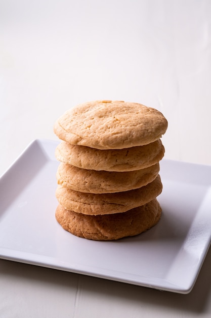 Pila casalinga di biscotti di biscotto al burro sulla tavola di legno del piatto bianco