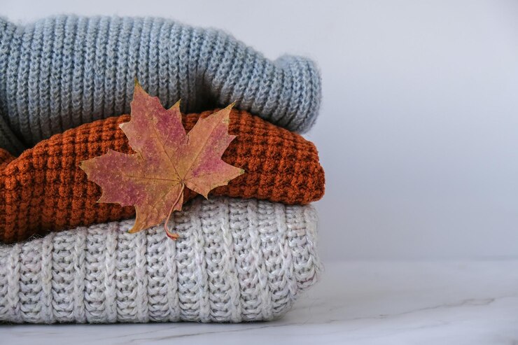Pila di accogliente maglione caldo lavorato a maglia con autunno autunno maple leaf Maglioni in stile retrò Colori arancione e blu Accogliente concetto hygge Copia spazio