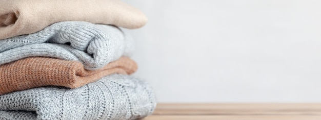 Pila di accoglienti maglioni lavorati a maglia su uno sfondo neutro Concetto caldo