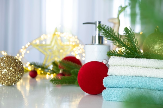 Pila di asciugamani blu e bianchi piegati sul tavolo rami di abete Palle di Natale e luci di Natale Massaggio SPA o salone di bellezza cura della pelle e cura del corpo nella variante di Natale o Capodanno