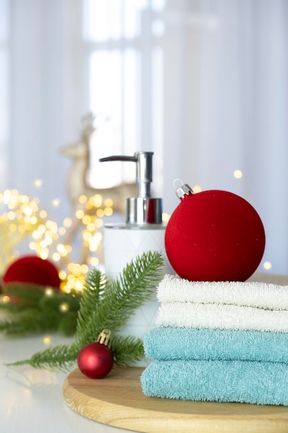 Pila di asciugamani blu e bianchi piegati sul tavolo rami di abete Palle di Natale e luci di Natale Massaggio SPA o salone di bellezza relax e benessere nella variante di Natale o Capodanno