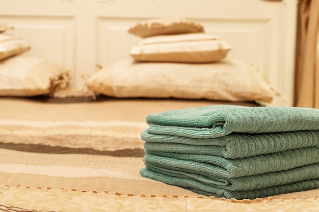 Pila di asciugamano verde dell'hotel sul letto nell'interno della camera da letto