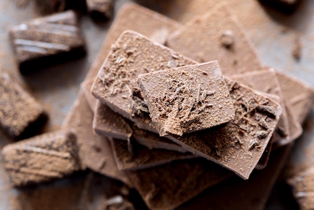 Pila di barrette di cioccolato Cioccolato al latte e fondente Caramelle al cioccolato Cacao in polvere sullo sfondo