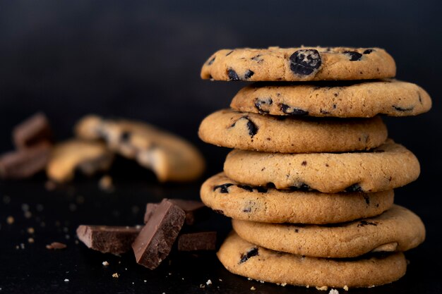 Pila di biscotti con gocce di cioccolato su sfondo nero