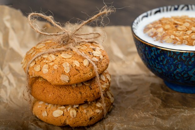 Pila di biscotti di farina d'avena con cereali e semi e ciotola di latte.