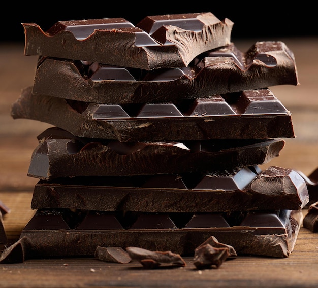 Pila di cioccolato rotto sulla tavola di legno