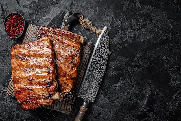 Pila di costolette di maiale alla griglia in salsa barbecue su un tagliere Sfondo nero Vista dall'alto Spazio di copia